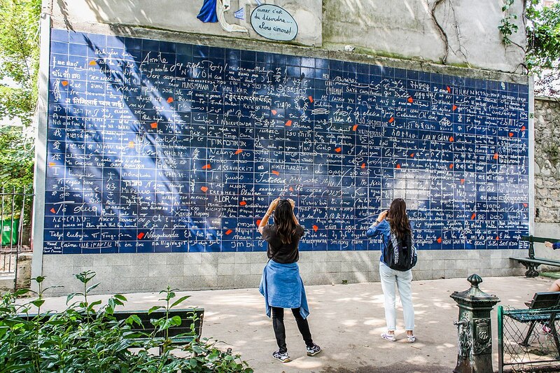 Pessoas fotografando o Muro do Eu Te Amo em Paris